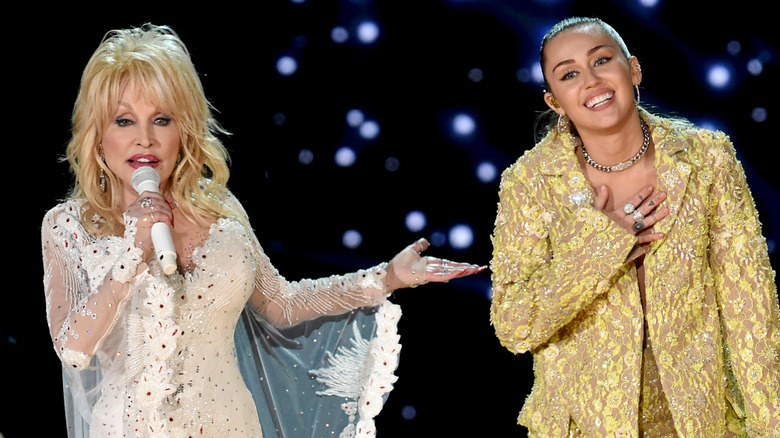 Dolly Parton motioning toward Miley Cyrus