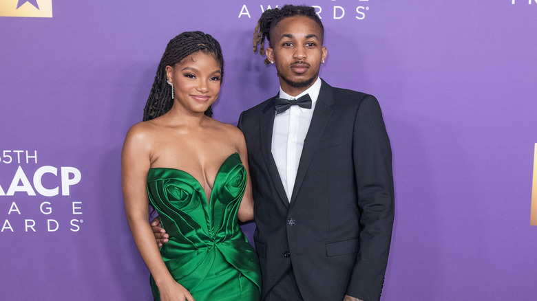 Halle Bailey and DDG pose in front of a purple wall