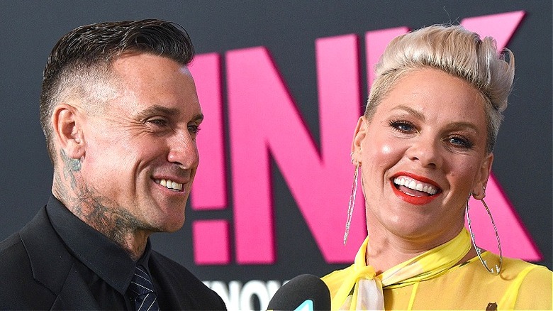 Pink speaking and smiling, next to husband Carey Hart, smiling