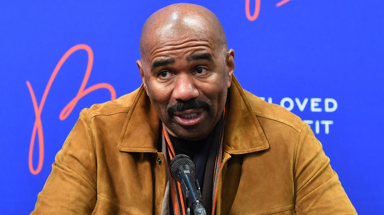 Steve Harvey sits at a press conference