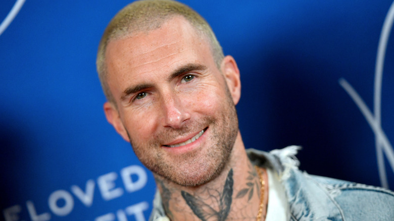 Adam Levine smiling with shaved head