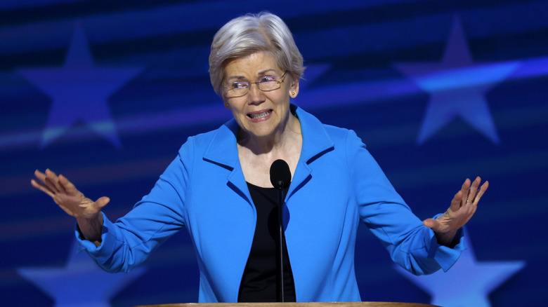 Elizabeth Warren giving a speech in front of a blue backdrop