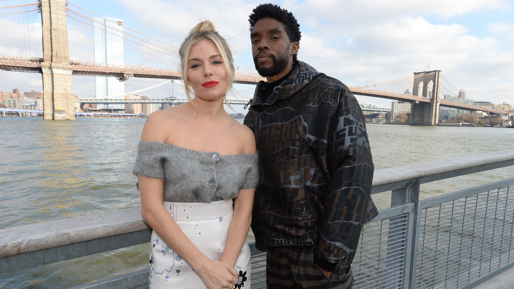 Sienna Miller and Chadwick Boseman in front of bridge