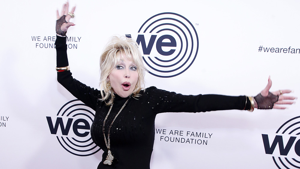 Dolly Parton with hands in the air on red carpet