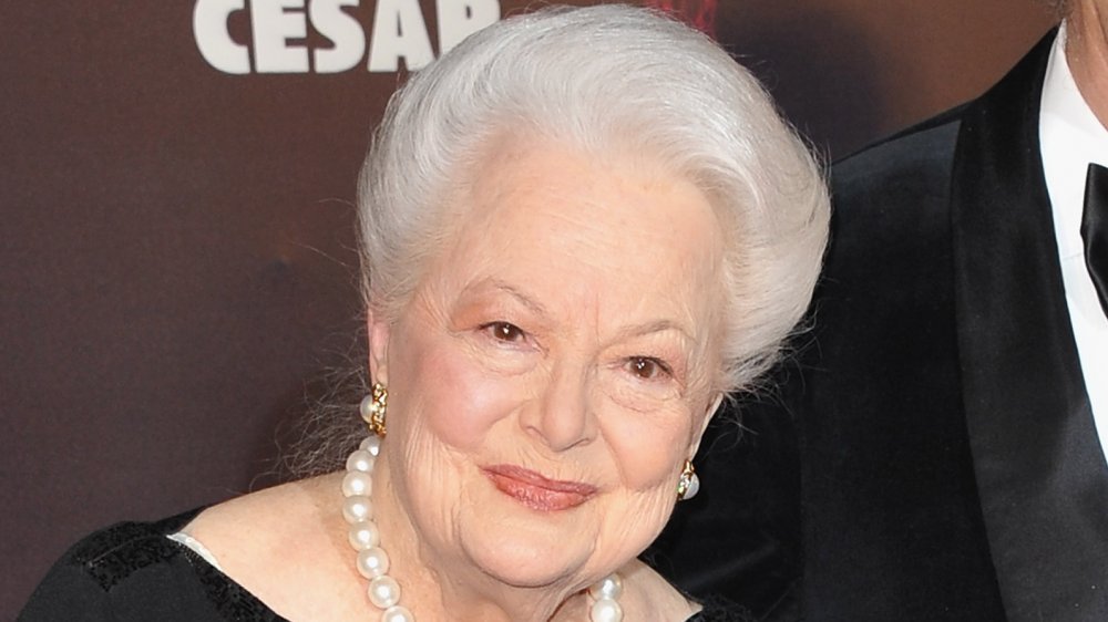 Olivia de Havilland in a black dress and pearls, smiling at a 2011 awards event