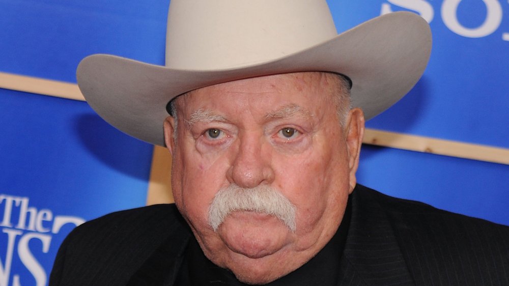 Wilford Brimley in a black suit and tan cowboy hat