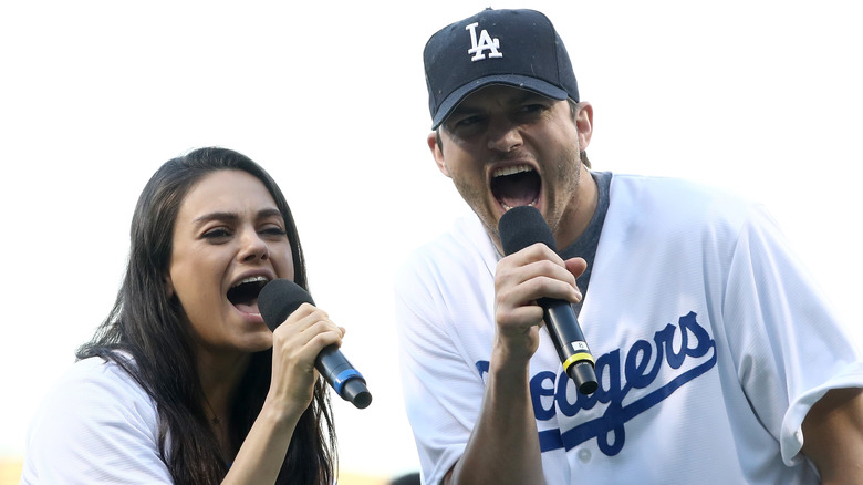 Mila Kunis, Ashton Kutcher with microphones, singing