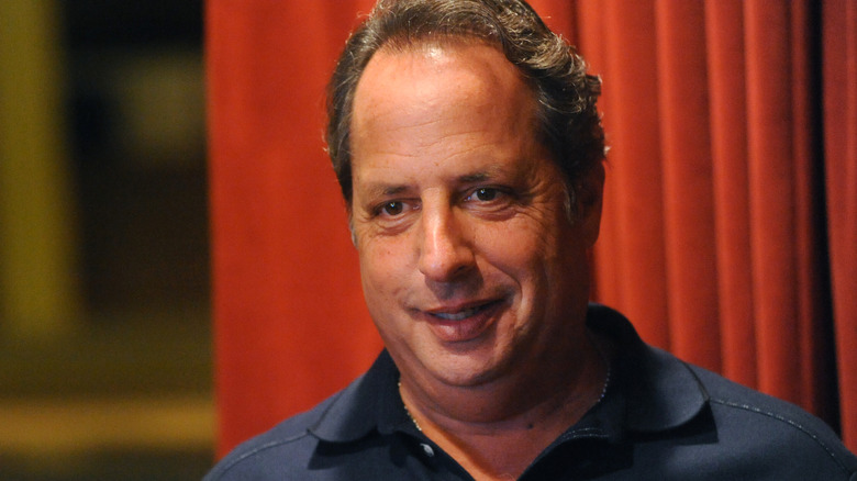 Jon Lovitz pictured in front of red curtains