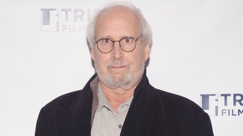 Chevy Chase wearing a jacket and glasses