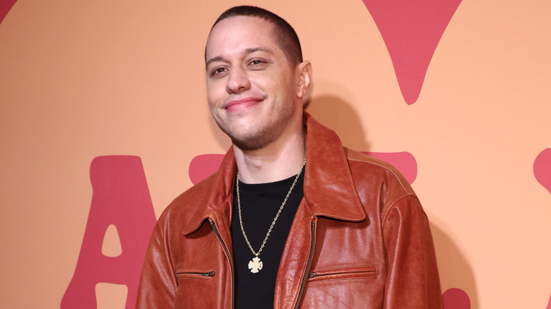 Pete Davidson smiling while wearing a leather jacket