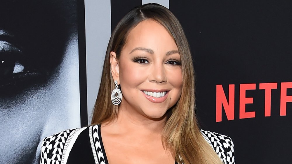 Mariah Carey smiling in front of Netflix promo wall