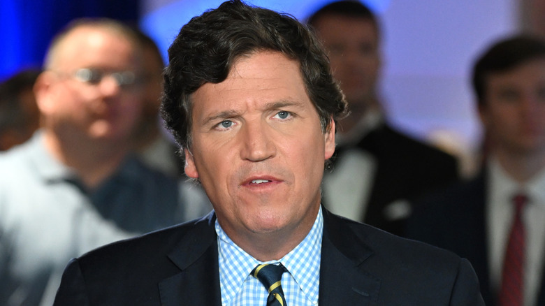 Tucker Carlson wearing a suit with a chered shirt