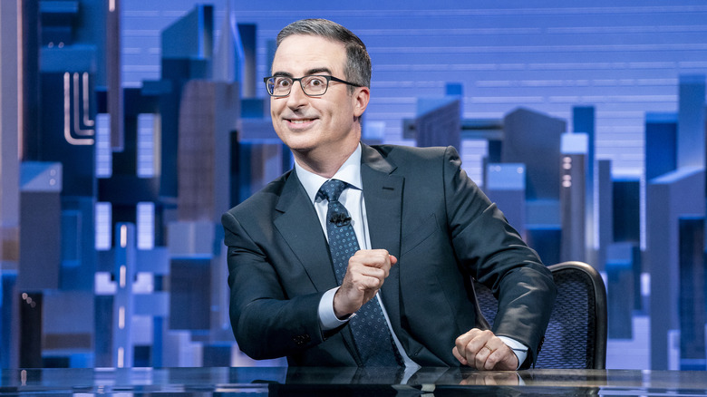 John Oliver sitting at his news desk