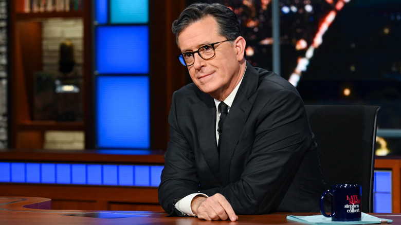 Stephen Colbert sitting at his news desk