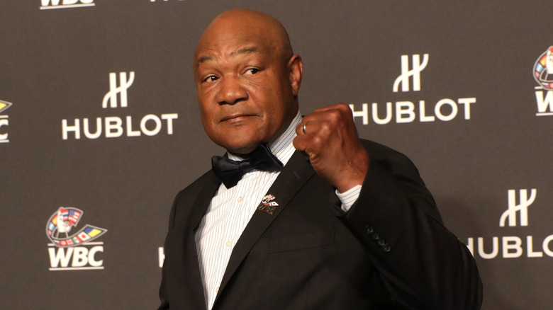 George Foreman with a fist up, wearing a suit