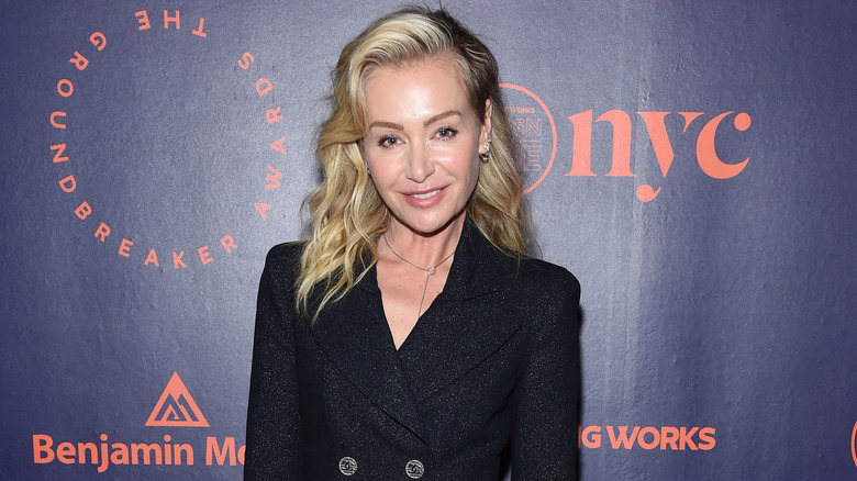 Portia de Rossi smiling in black, sparkly trench coat dress