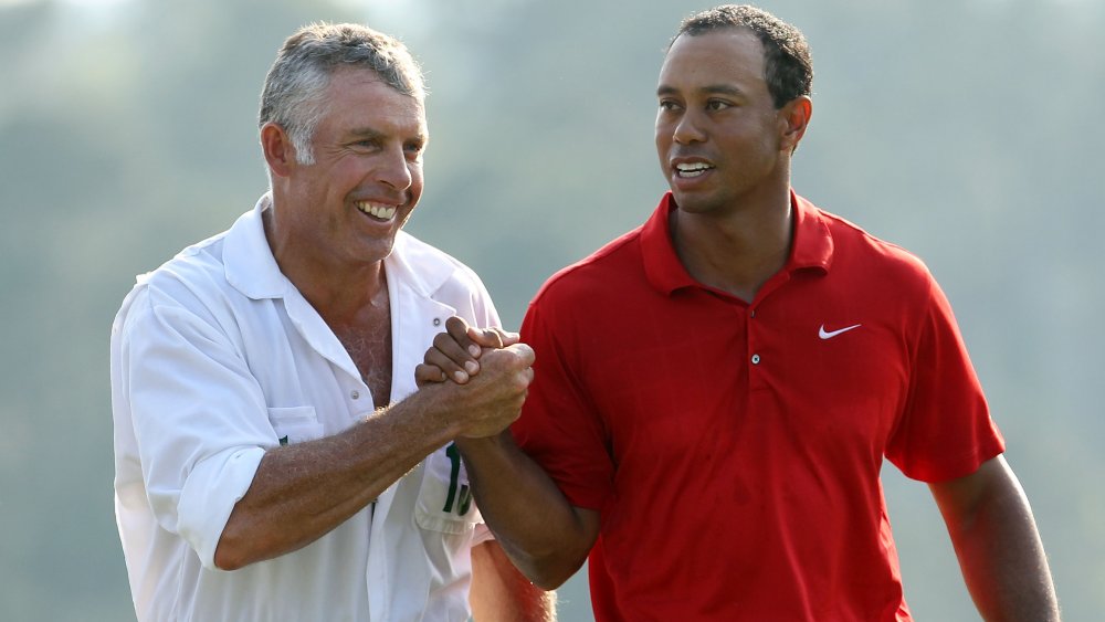 Steve Williams and Tiger Woods handshaking and smiling out on the golf course