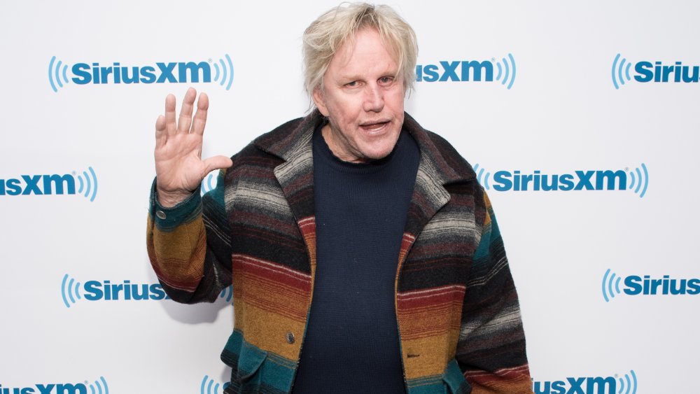 Gary Busey waving in front of SiriusXM wall