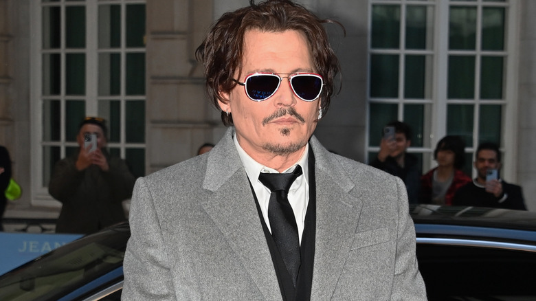 Johnny Depp wearing sunglasses in gray overcoat