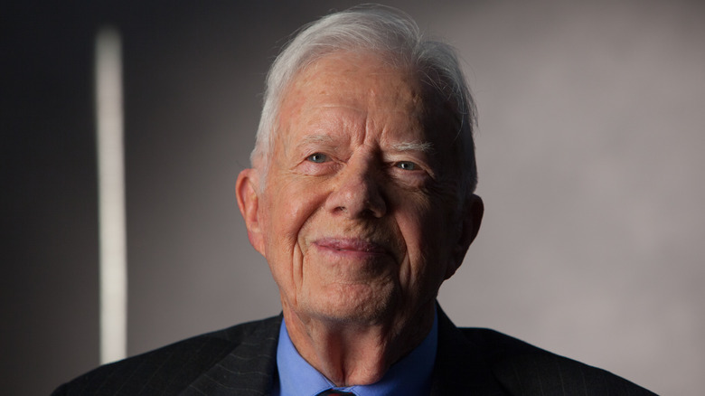 Jimmy Carter wearing a blue collared shirt and smiling