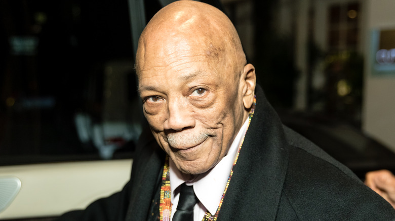 Quincy Jones wearing a black coat and white shirt