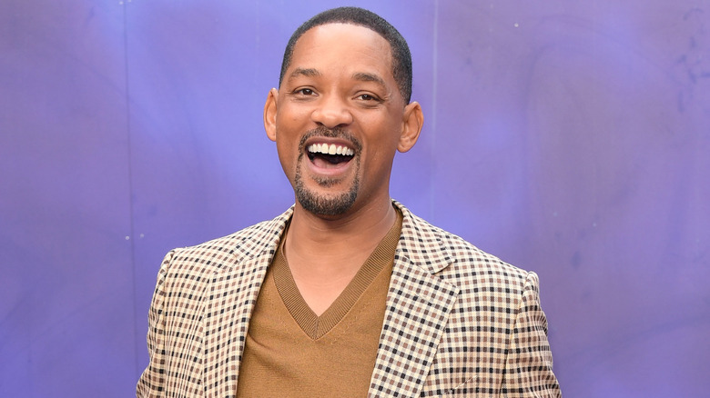 Will Smith with mouth open wide wearing brown checkered jacket