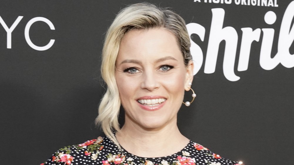 Elizabeth Banks a black, white-polka dotted, floral dress, posing with a smile at an event