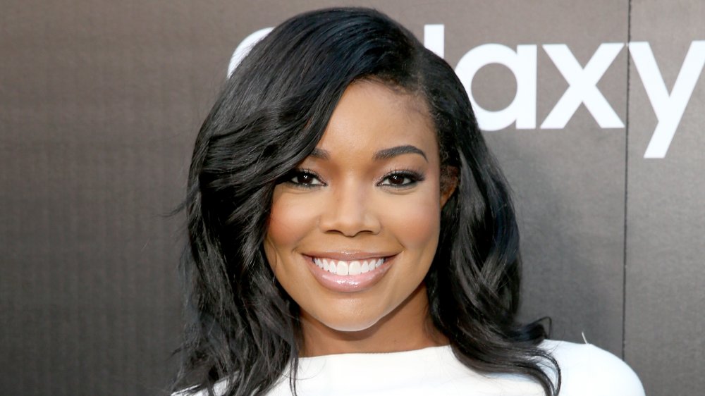 Gabrielle Union in a white dress, smiling big at a red carpet event