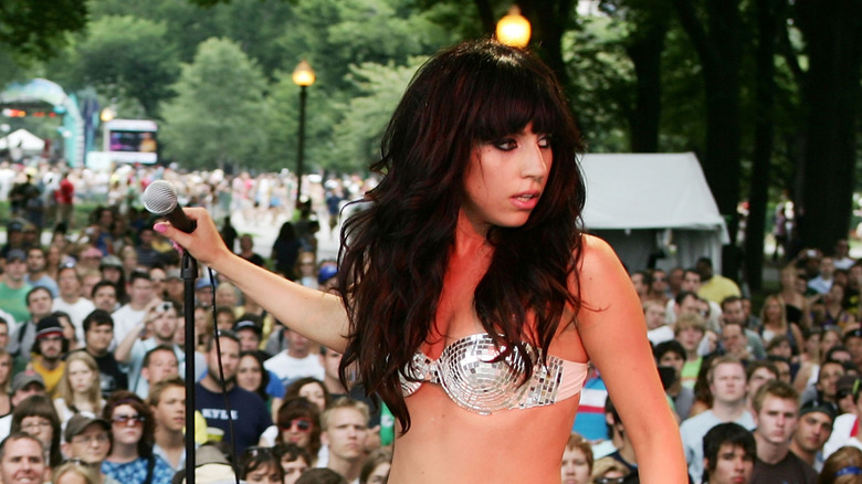 Lady Gaga with dark brown hair and bands wearing a disco studded strapless bra