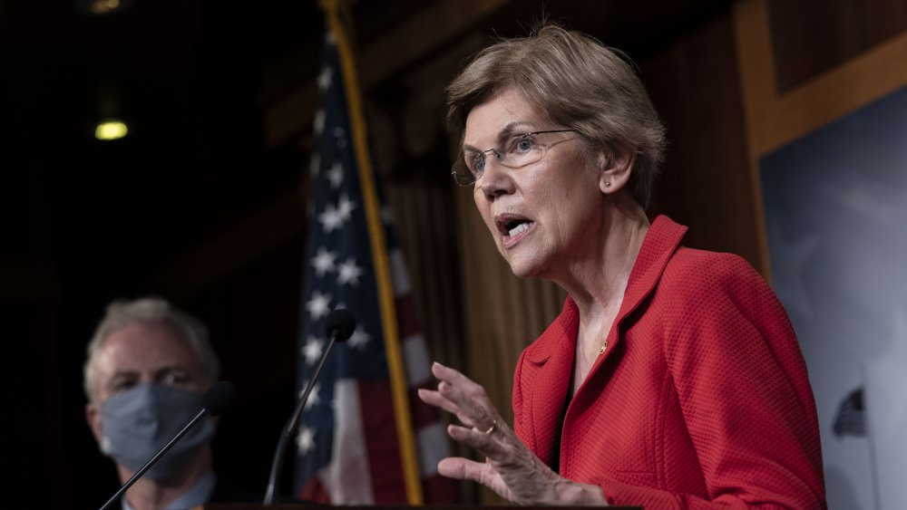 Sen. Elizabeth Warren in a red blazer, speaking during a political event