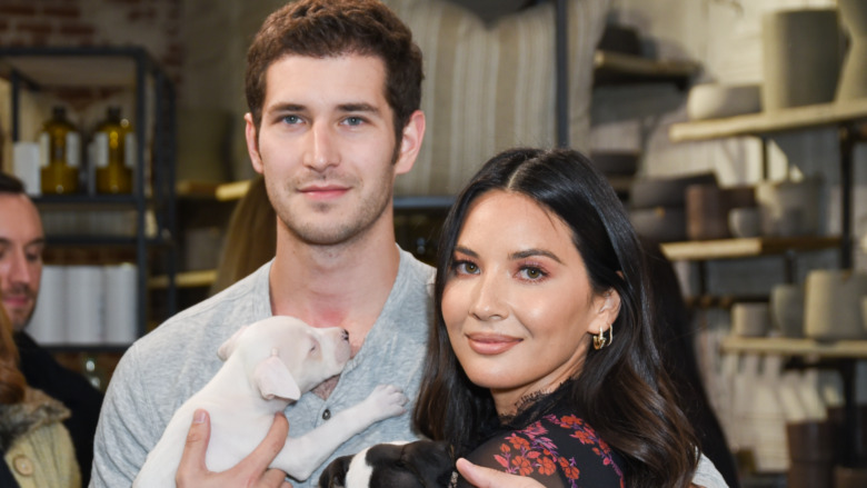 Olivia Munn and Tucker Roberts smiling and holding puppies 