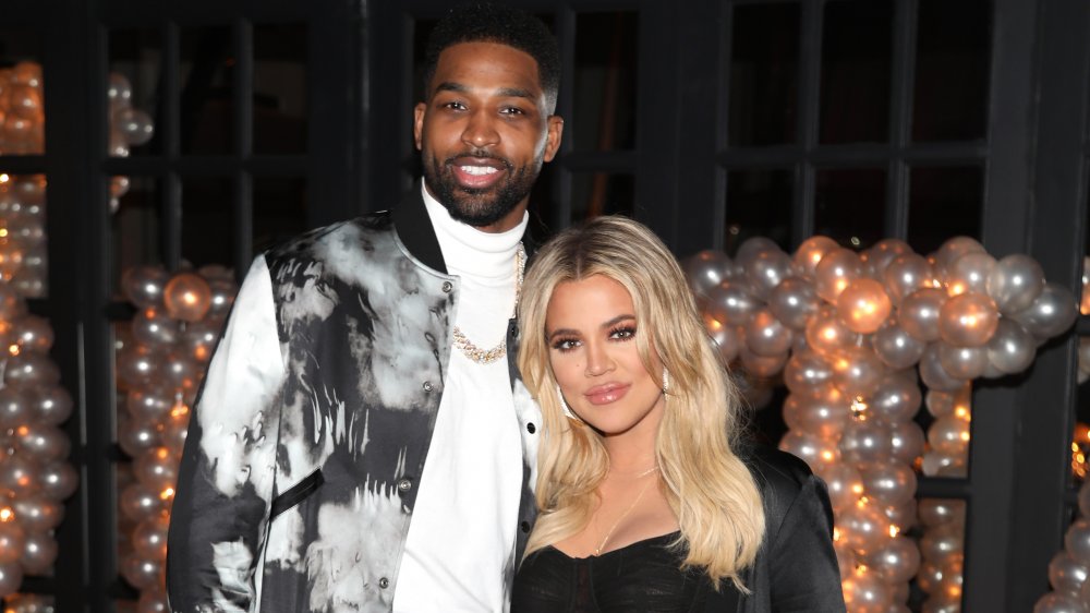 Tristan Thompson and Khloe Kardashian smiling together in front of a bunch of balloons