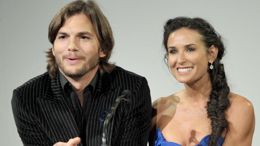 Ashton Kutcher and Demi Moore standing by each other behind a podium and smiling