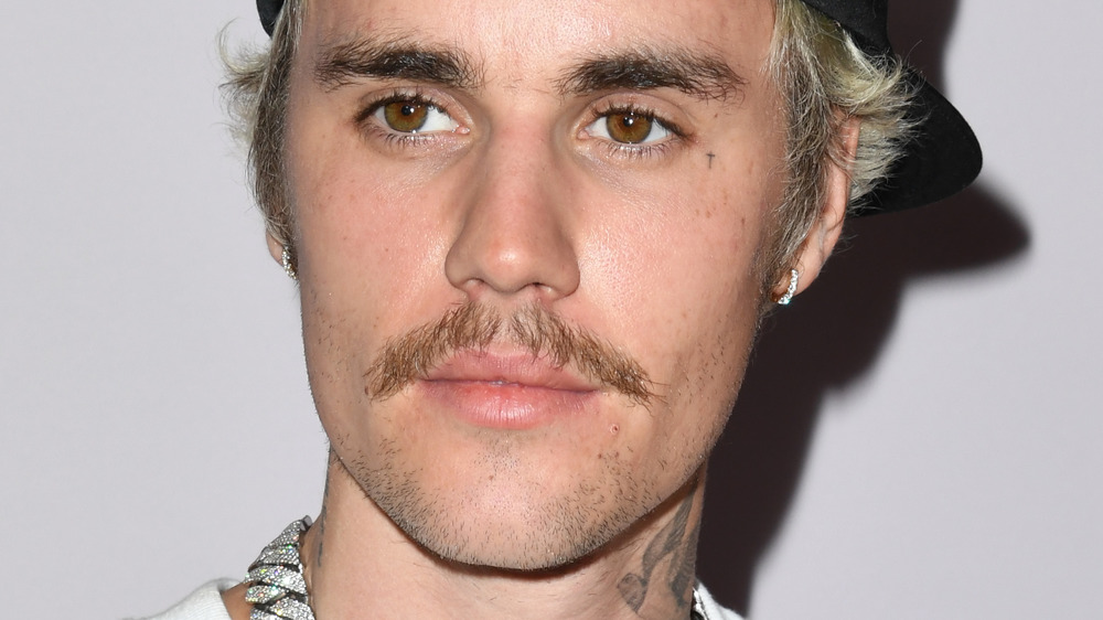 A mustachioed Justin Bieber looking serious 