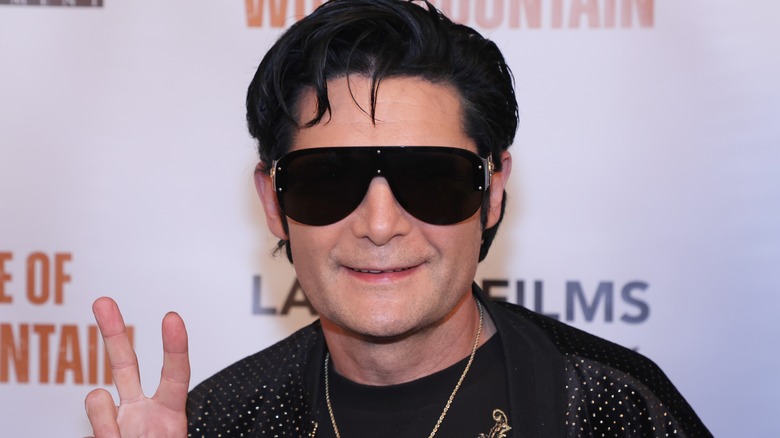 Corey Feldman smiling peace sign in sunglasses