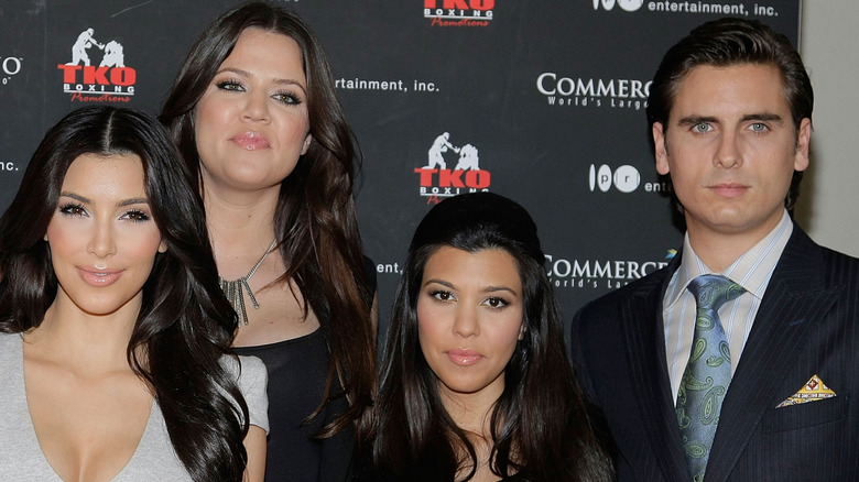 Kardashian sisters posing with Scott Disick