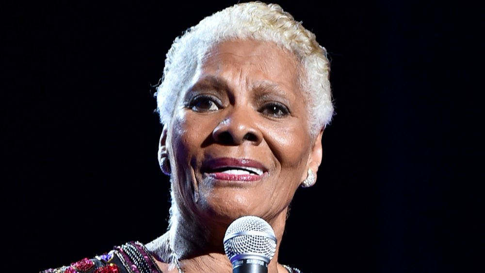 Dionne Warwick wearing a black and bejeweled top, singing