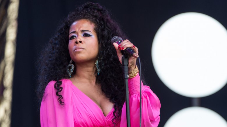 Kelis in a pink, flowing dress, looking serious during a live concert gig