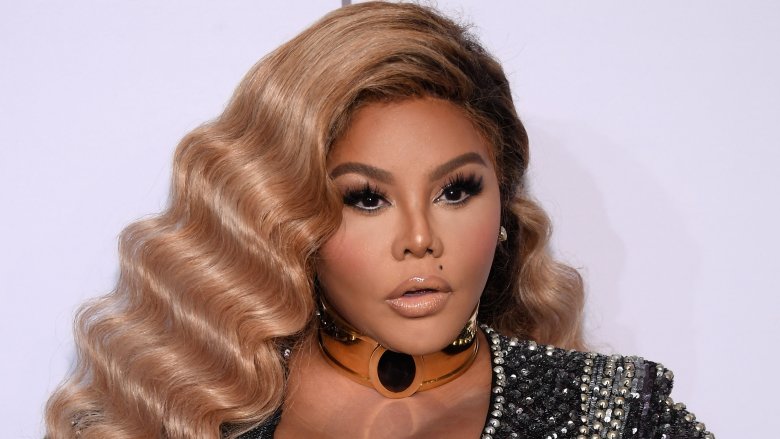 Lil' Kim wearing a bejeweled black dress, looking surprised on the red carpet