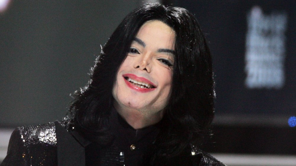 Michael Jackson wearing all black, smiling during a performance