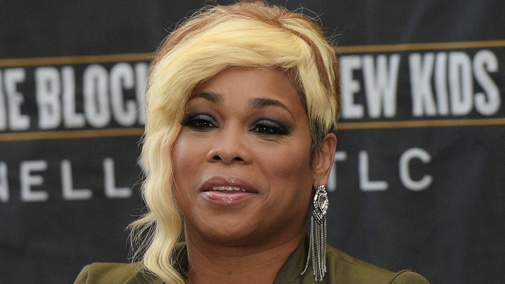 Tionne 'T-Boz' Watkins wearing a green outfit and large, dangling earrings, half-smiling at an event