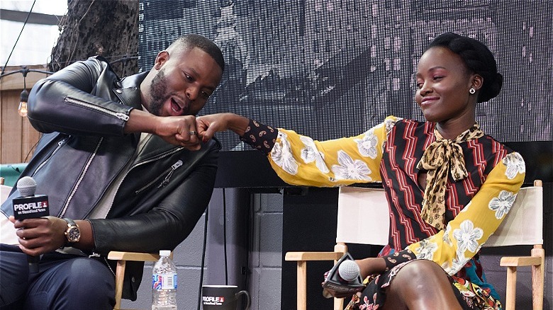 Winston Duke and Lupita Nyong'o doing a fist bump