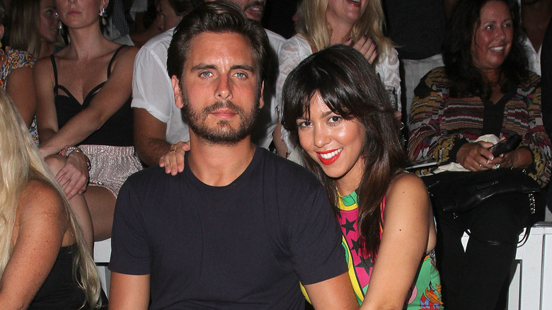 A stonefaced Scott Disick next to a smiling Kourtney Kardashian