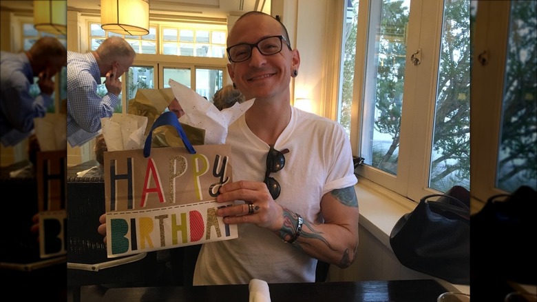 Chester Bennington smiling while holding up a birthday present