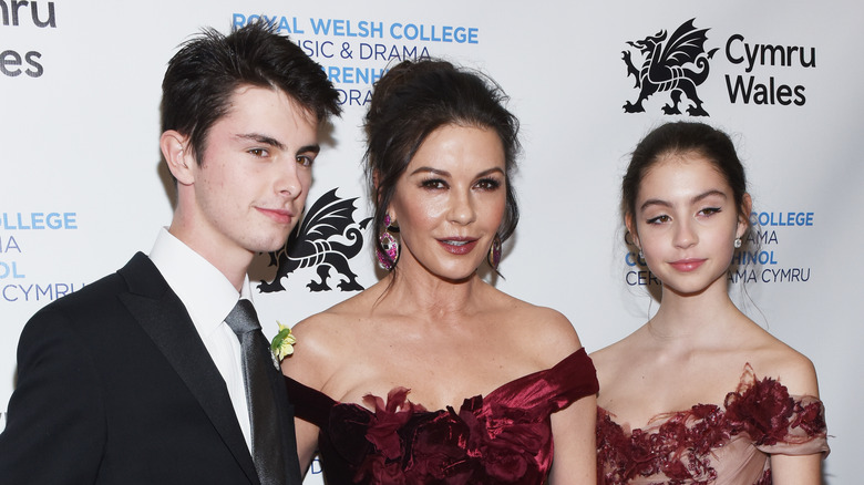 Catherine Zeta-Jones posing on a red carpet with Dylan Michael Douglas and Carys Zeta Douglas