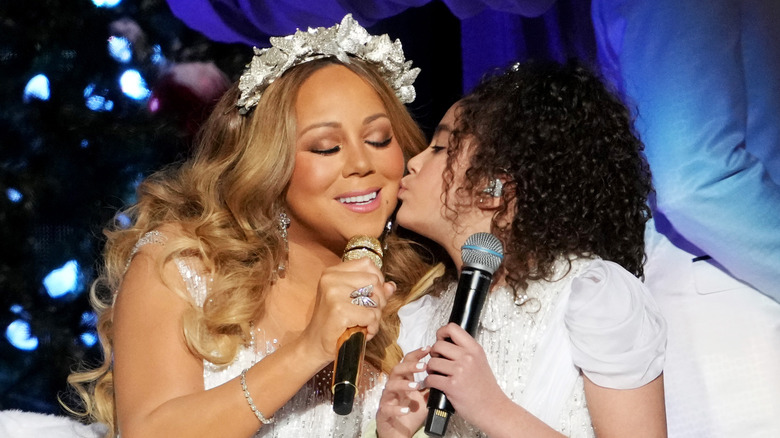 Monroe Cannon kissing Mariah Carey and holding a microphone