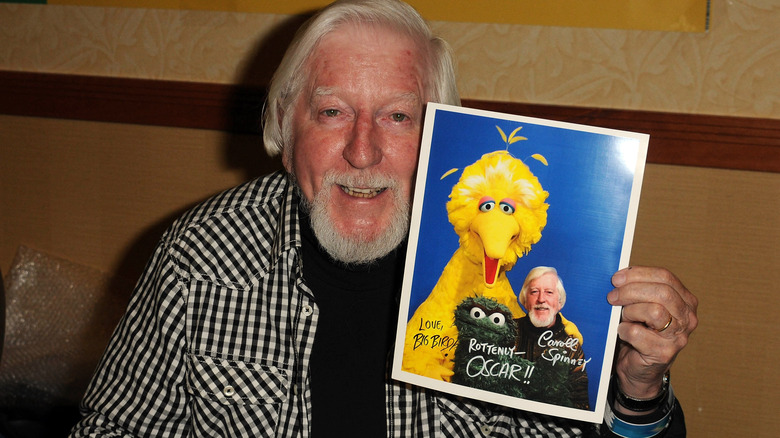 Carroll Spinning posing with a headshot of his "Sesame Street" characters