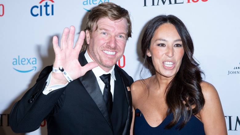 Chip Gaines waving next to a smiling Joanna Gaines 