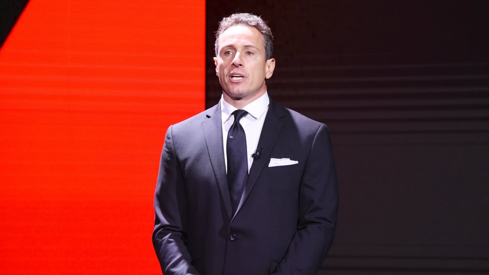 Chris Cuomo speaking in front of black and red wall