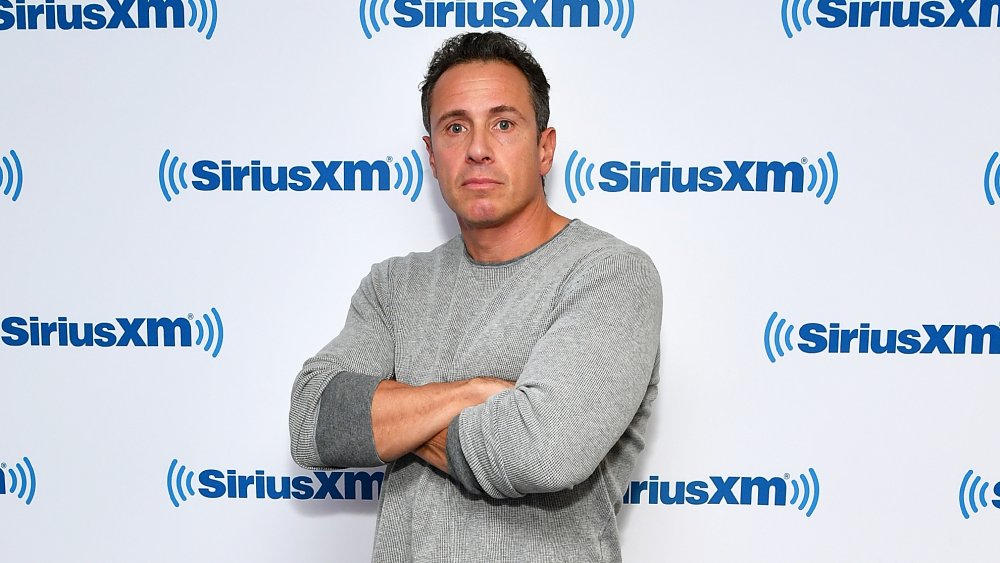 Chris Cuomo, arms crossed, in front of SiriusXM wall